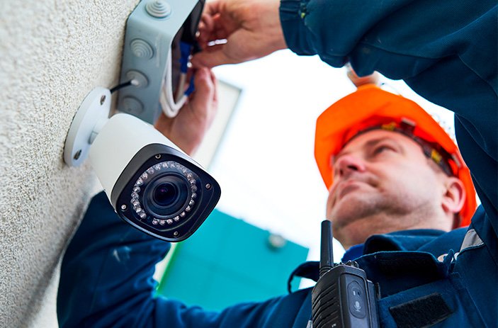 Técnico instalando câmera de segurança em parede para sistema de monitoramento por vídeo