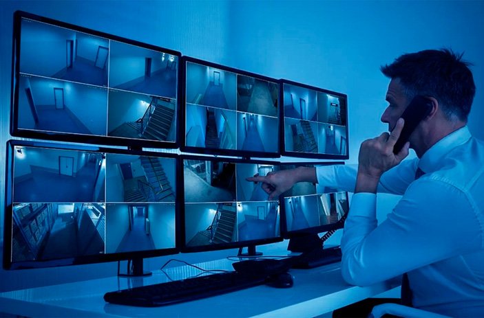 Operador em central de monitoramento 24h observando imagens de câmeras de segurança em tempo real